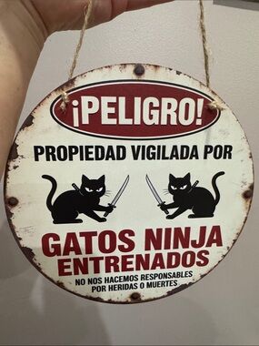 Funny cat ninja Tin warning sign in Spanish